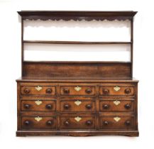 An 18th century oak and walnut crossbanded dresser, the plate rack and solid back over an