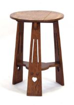 An Arts & Crafts oak occasional table, the circular surface over a second tier, on three splayed