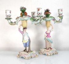A pair of late 19th/early 20th century Meissen figural two branch candlesticks modelled as a