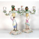 A pair of late 19th/early 20th century Meissen figural two branch candlesticks modelled as a