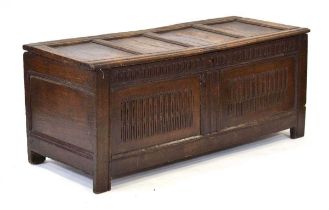 An 18th century oak coffer of long proportions, the four-panelled surface over two later carved