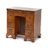 A George III walnut, feather banded and crossbanded kneehole desk with eight drawers and a