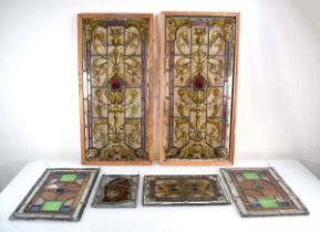 A pair of stained glass and leaded panels in later pine frames, 63 x 31 cm, together with four