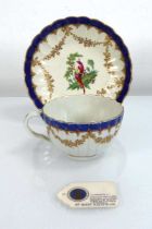 An early Worcester tea cup and saucer dish, each decorated with an exotic bird with a blue and