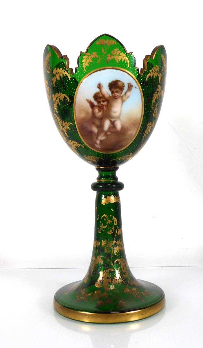 A Bohemian green glass vase of goblet form decorated with a pair of putti within a gilt fern
