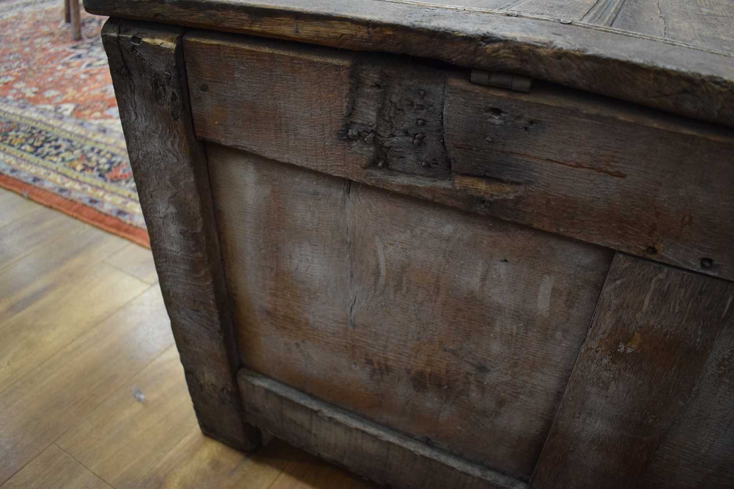 An 18th century oak coffer of long proportions, the four-panelled surface over two later carved - Image 8 of 16