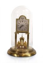 An anniversary clock, the silvered dial inscribed 'Tempus Fugit', the brass body below a glass dome,