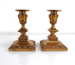 A pair of 19th century brass candlesticks with removeable sconces, decorated in the neo-classical