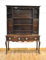 A Georgian oak dresser, the plate rack with two panelled doors over two drawers, a shaped apron