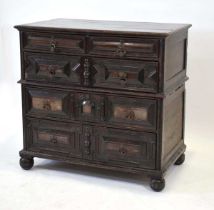 An early 18th century oak panelled chest of two short over three long drawers, each with geometric