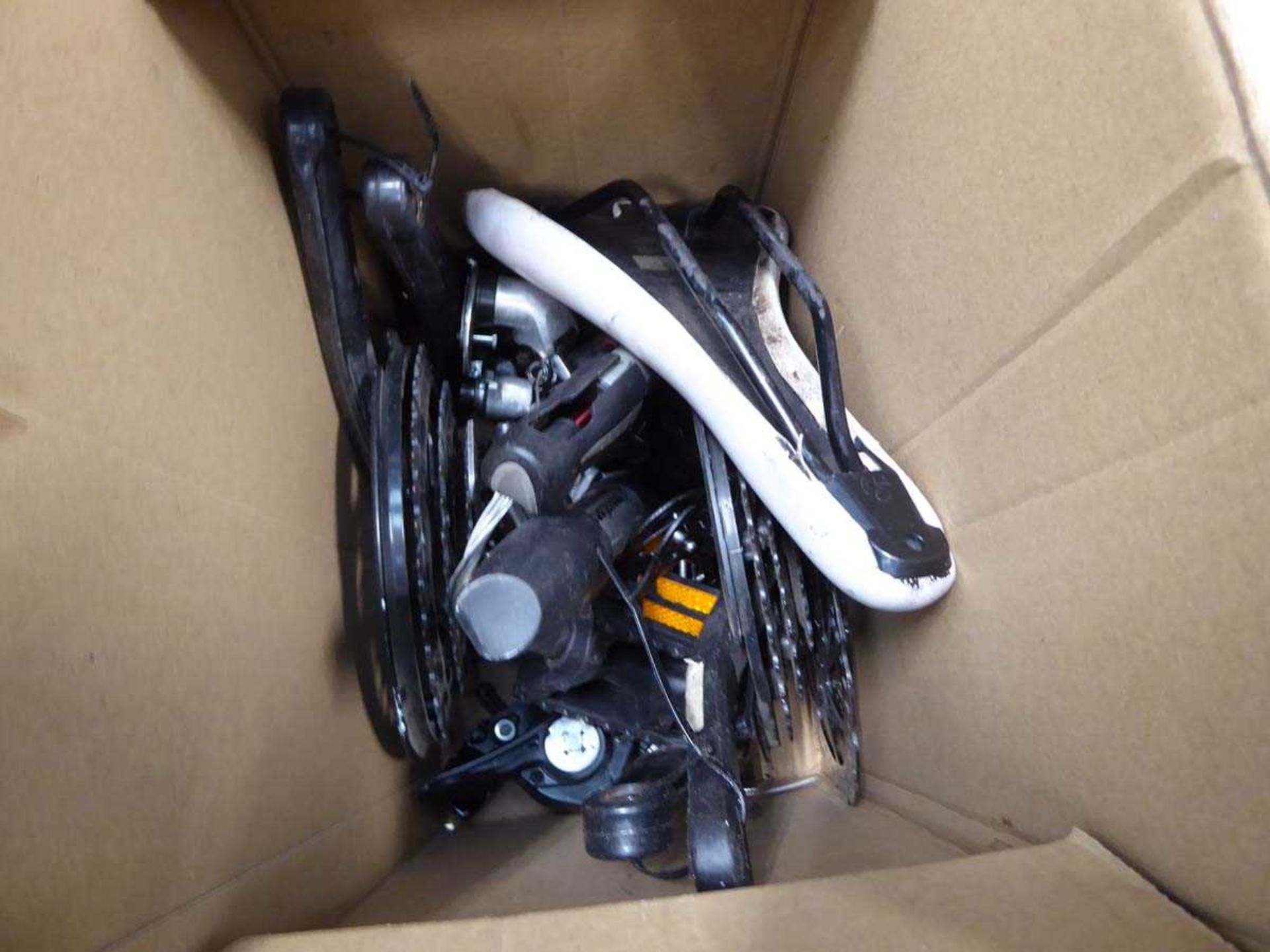Box containing used bike seat, pedals and pumps