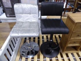 2 stools, 1 in metallic silver upholstered finish, the other with a black leatherette finish