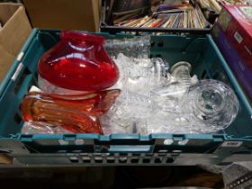Green plastic crate containing various glassware including a red glass vases