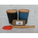 +VAT Pair of Le Creuset storage jars with wooden lids, one in teal and one in black, together with a