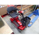 Four wheeled red mobility scooter with charger