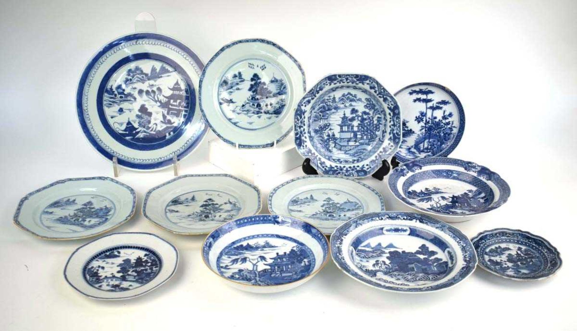 A set of four Chinese blue and white side plates, each decorated with a pine tree landscape by a