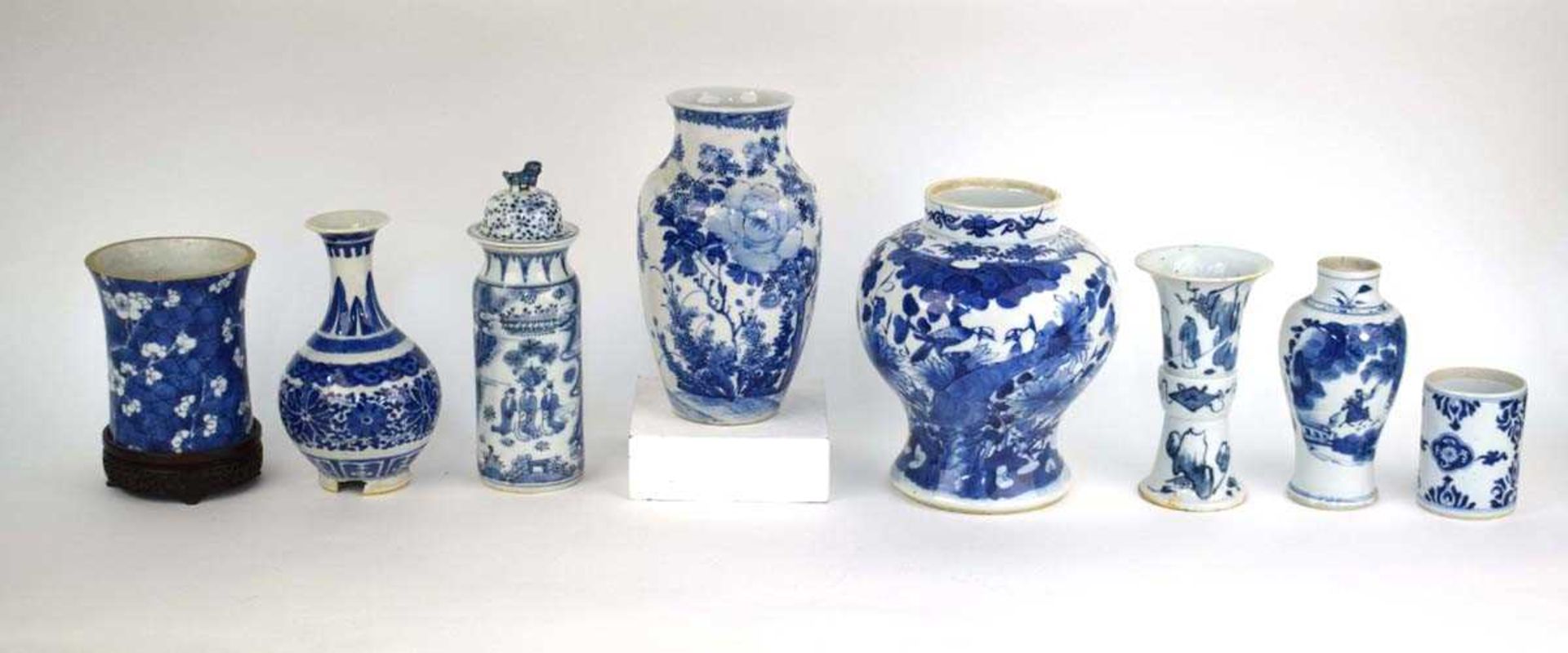 A Chinese blue and white blossom pattern brush pot of cylindrical form on a fixed hardwood base,