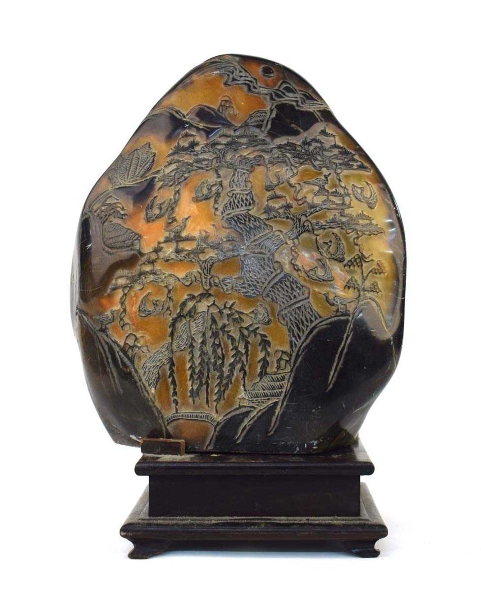 A Chinese carved soapstone ornament of natural form, carved with pine trees within an extensive