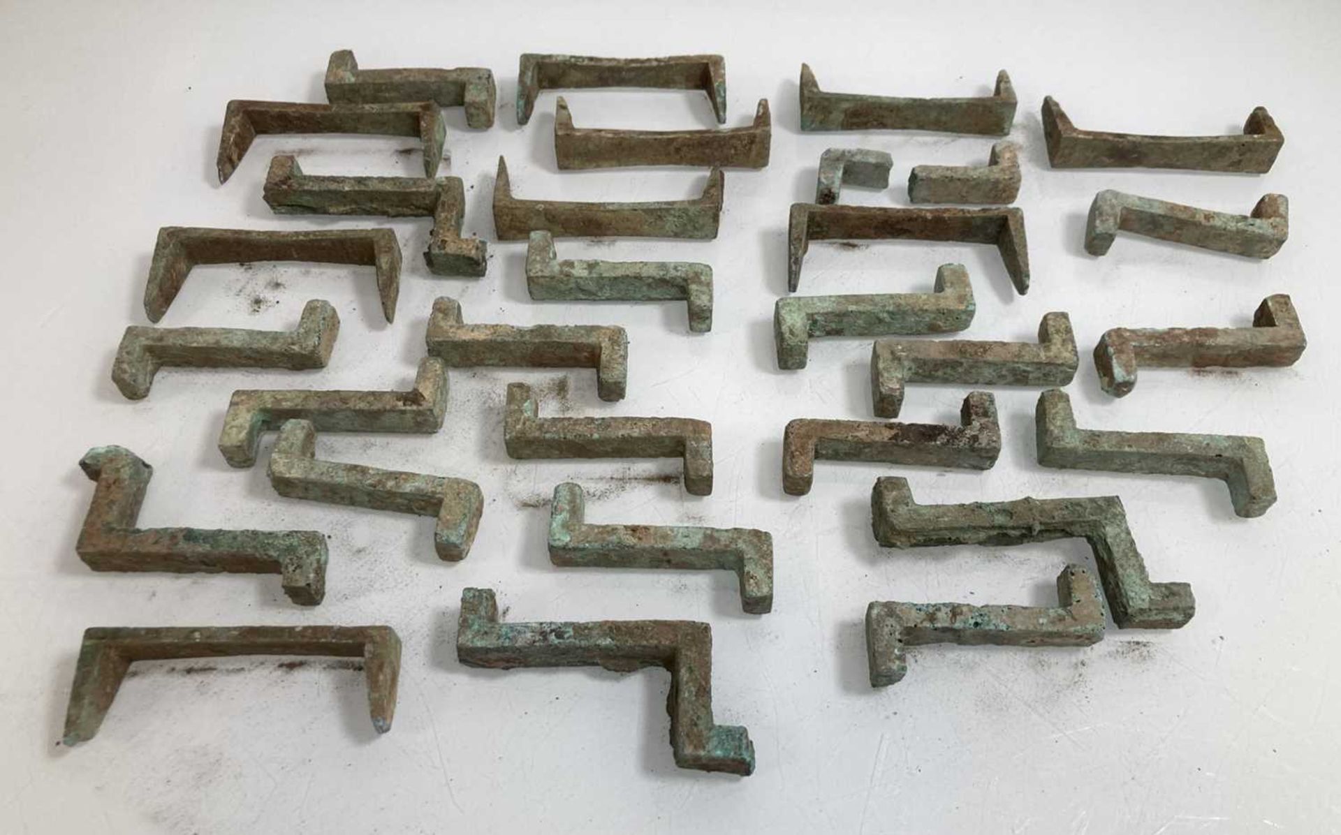 A group of green patinated bronze brackets of archaic form, max l. 10 cm (30)