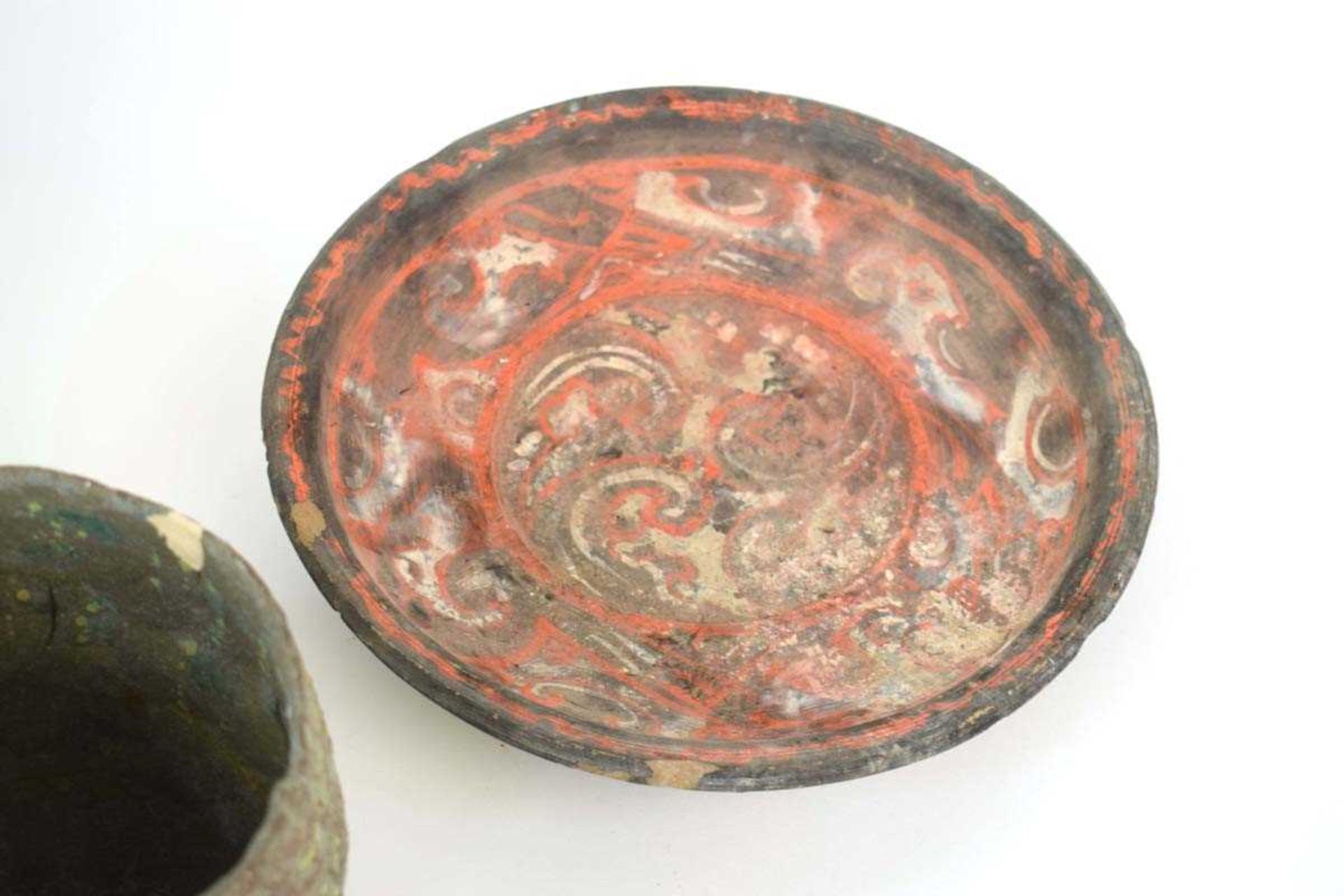 A Chinese archaic pottery plate of circular form decorated with scrolls in black and red glazes, - Bild 2 aus 3