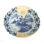 A Japanese blue and white dish of scalloped form, centrally decorated with an extensive landscape on