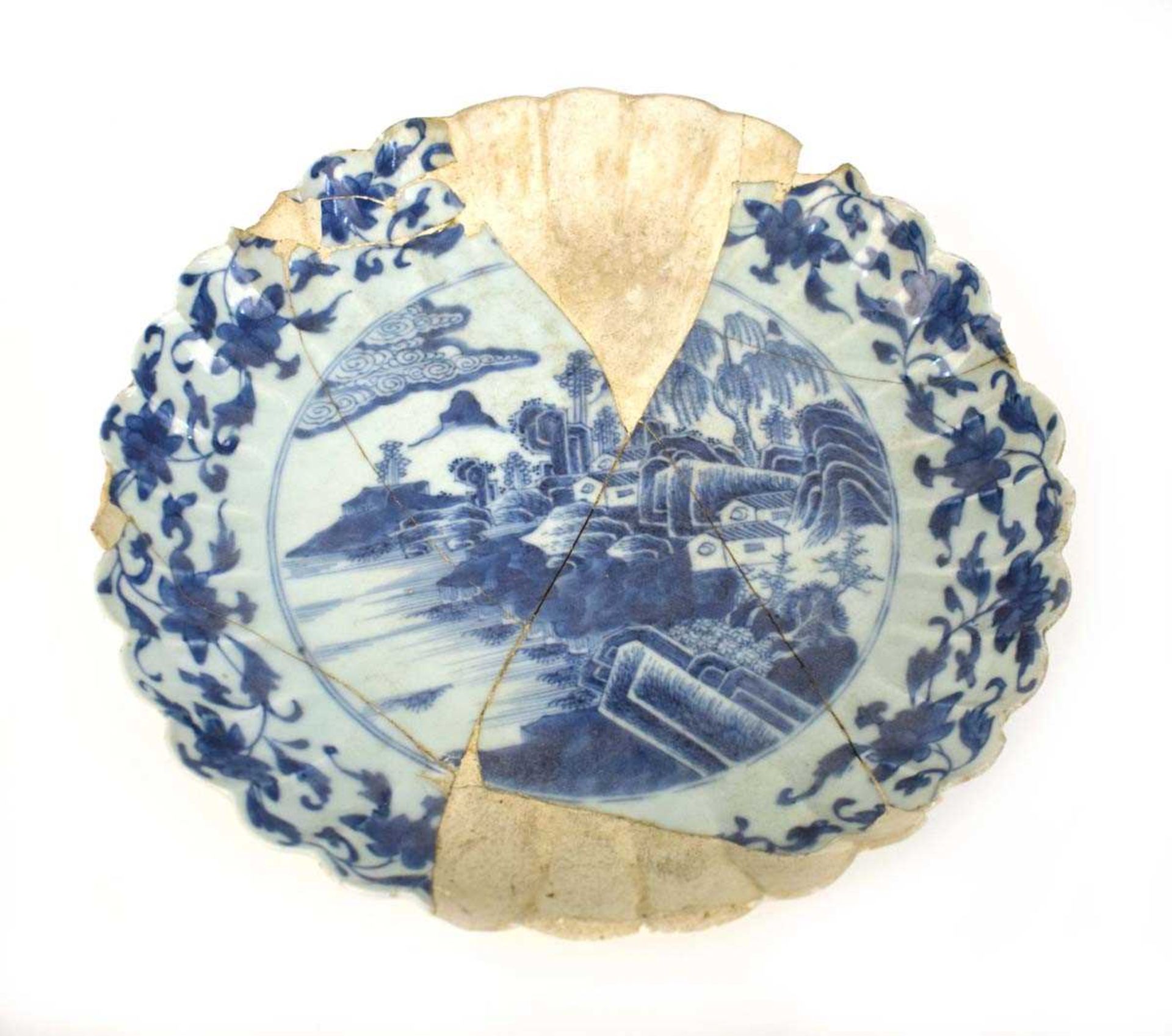 A Japanese blue and white dish of scalloped form, centrally decorated with an extensive landscape on