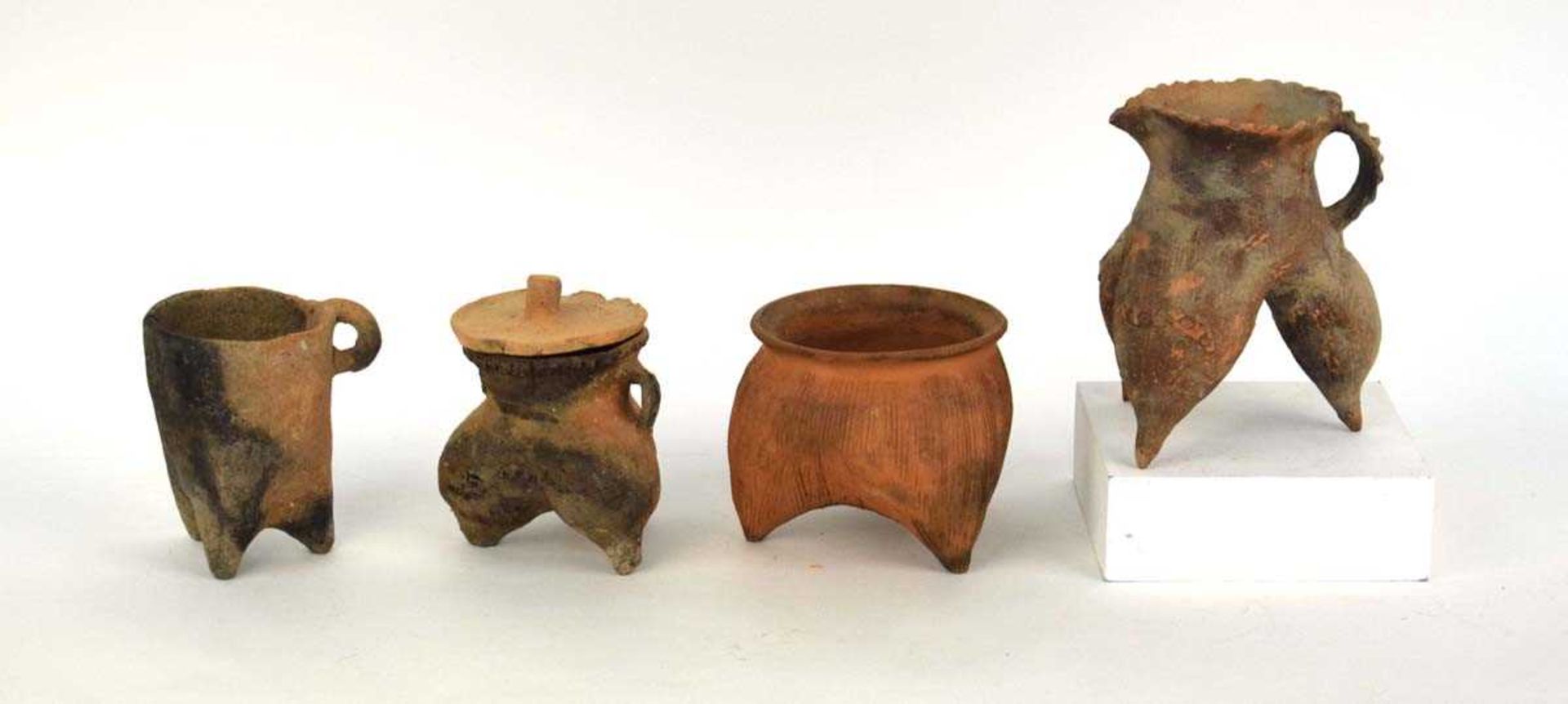 A Chinese archaic pottery jug of tripod form, h. 16 cm, together with three similar vessels (4) *