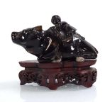 A Chinese hardstone carving modelled as a water buffalo and rider on a carved hardwood stand,