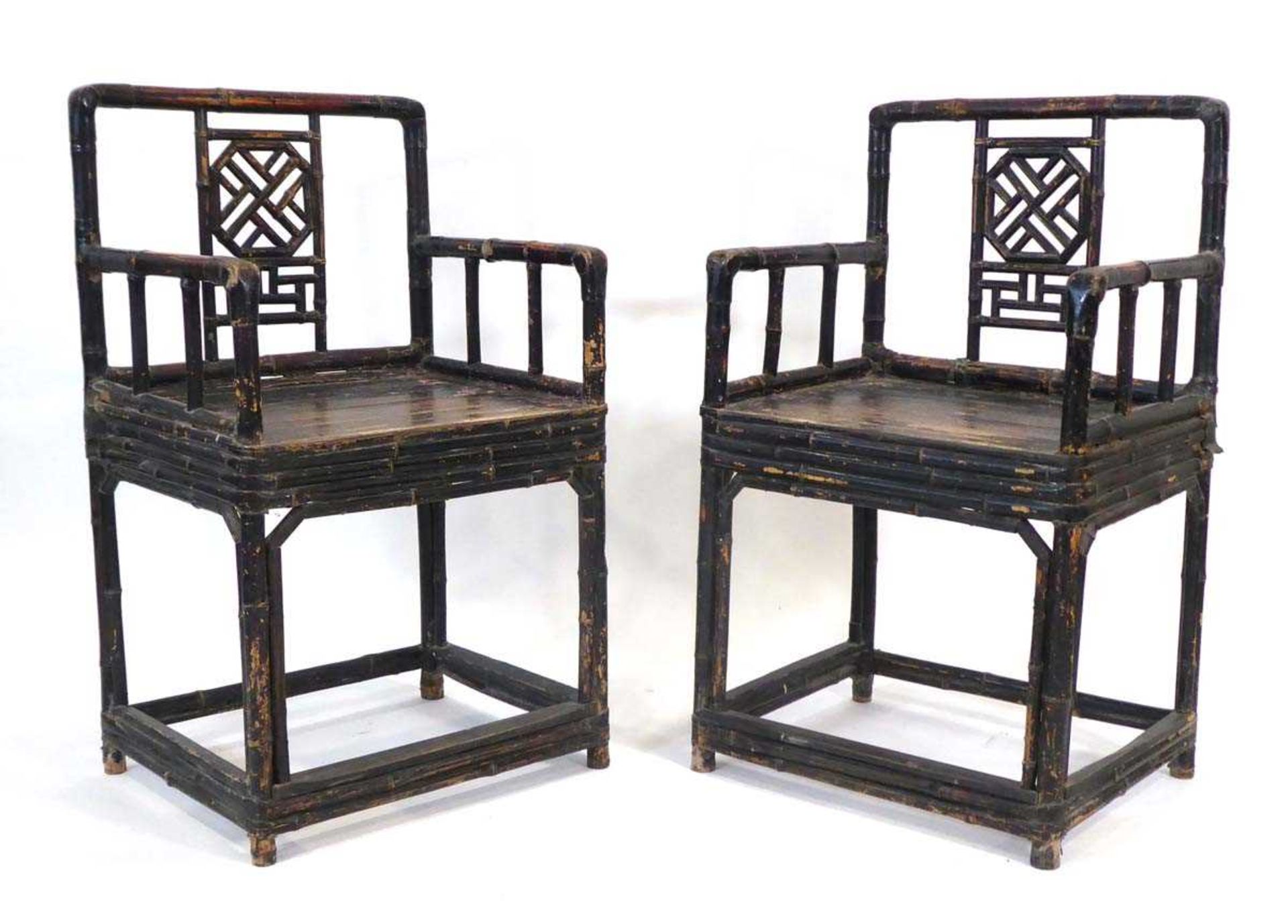 A pair of Chinese bamboo and lacquered elbow chairs with decorative trellis splats, solid seats