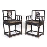 A pair of Chinese bamboo and lacquered elbow chairs with decorative trellis splats, solid seats