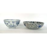 A Japanese blue and white bowl, centrally decorated with a shrubs within a scrolled border,