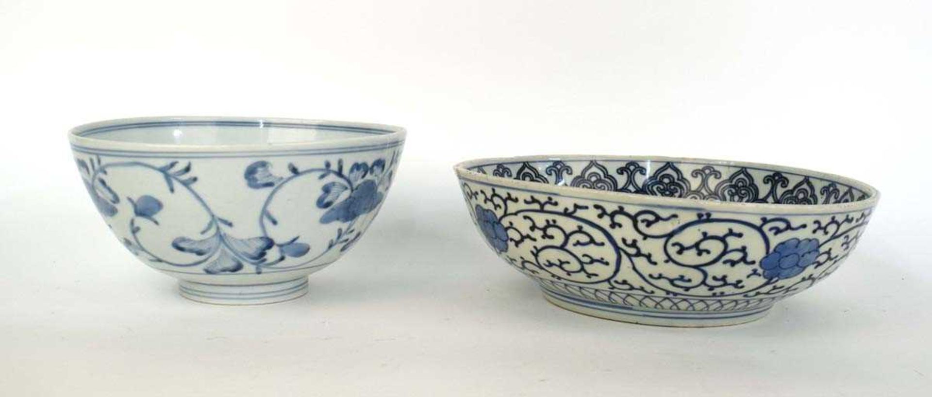 A Japanese blue and white bowl, centrally decorated with a shrubs within a scrolled border,