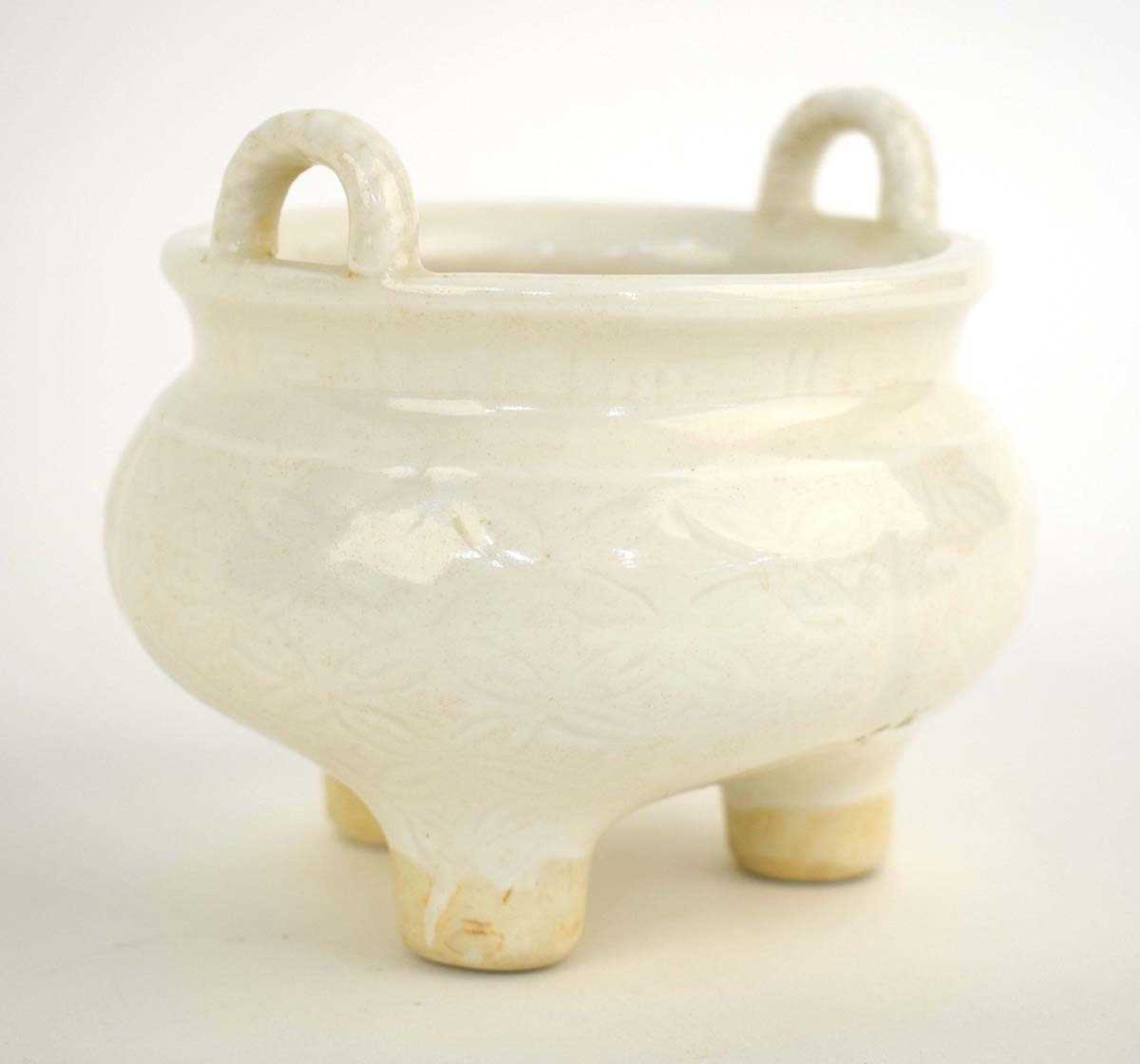 A Chinese blanc de chine two handled incense burner of squat form, incised with stylised