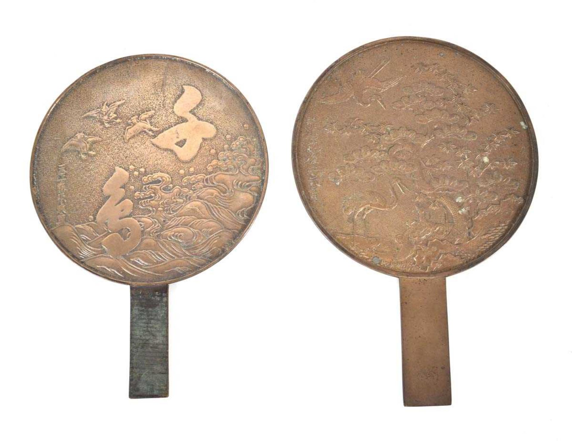 Two Chinese cast metal mirrors, one depicting cranes by a pine tree, l. 31.5 cm (2) *from the