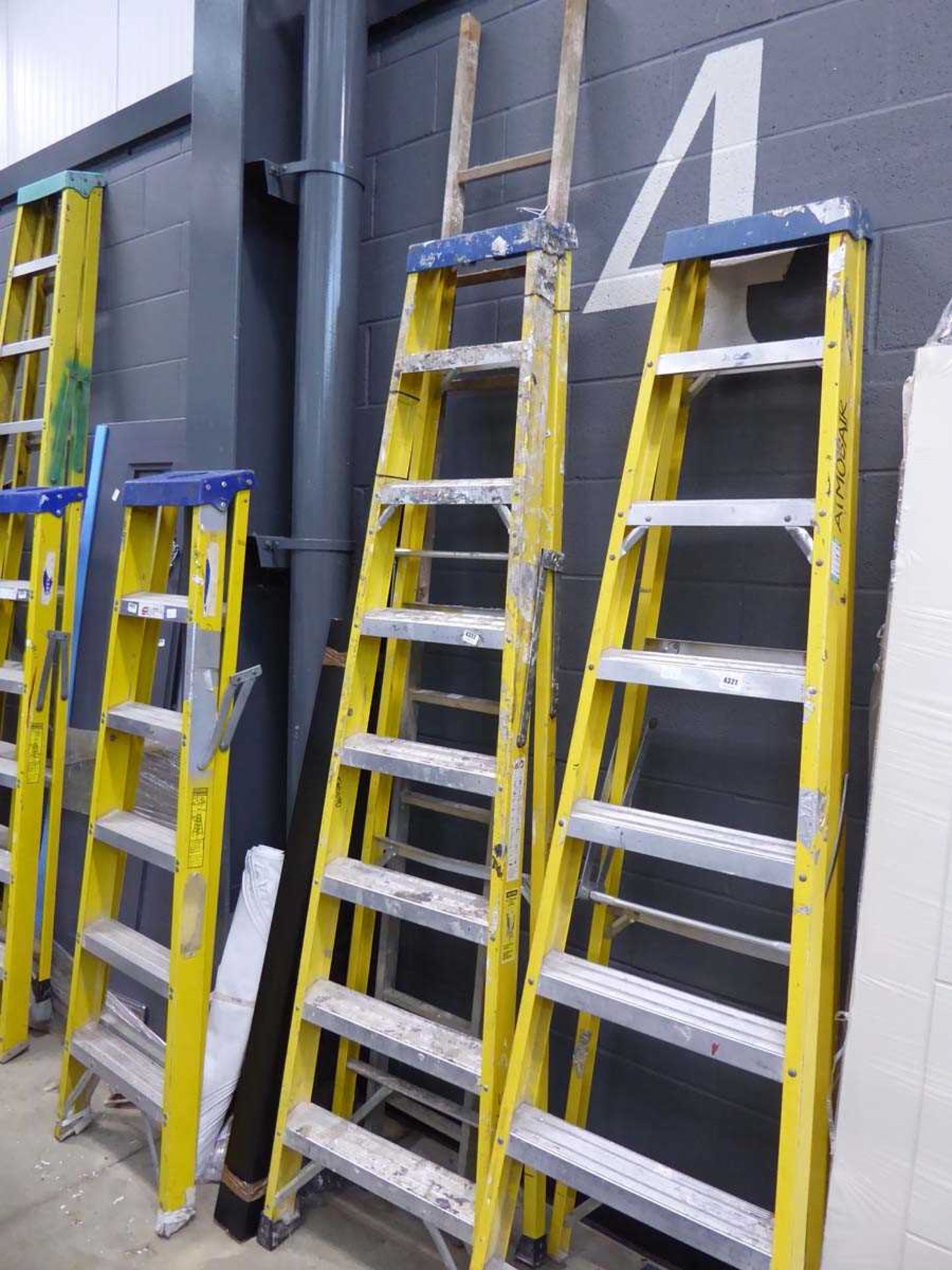 8 tread yellow and silver electricians style stepladder and a single section of an aluminium ladder