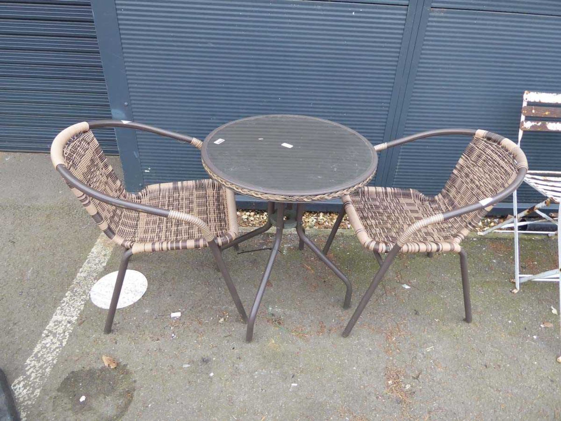 Two rattan style chairs and round glass top table