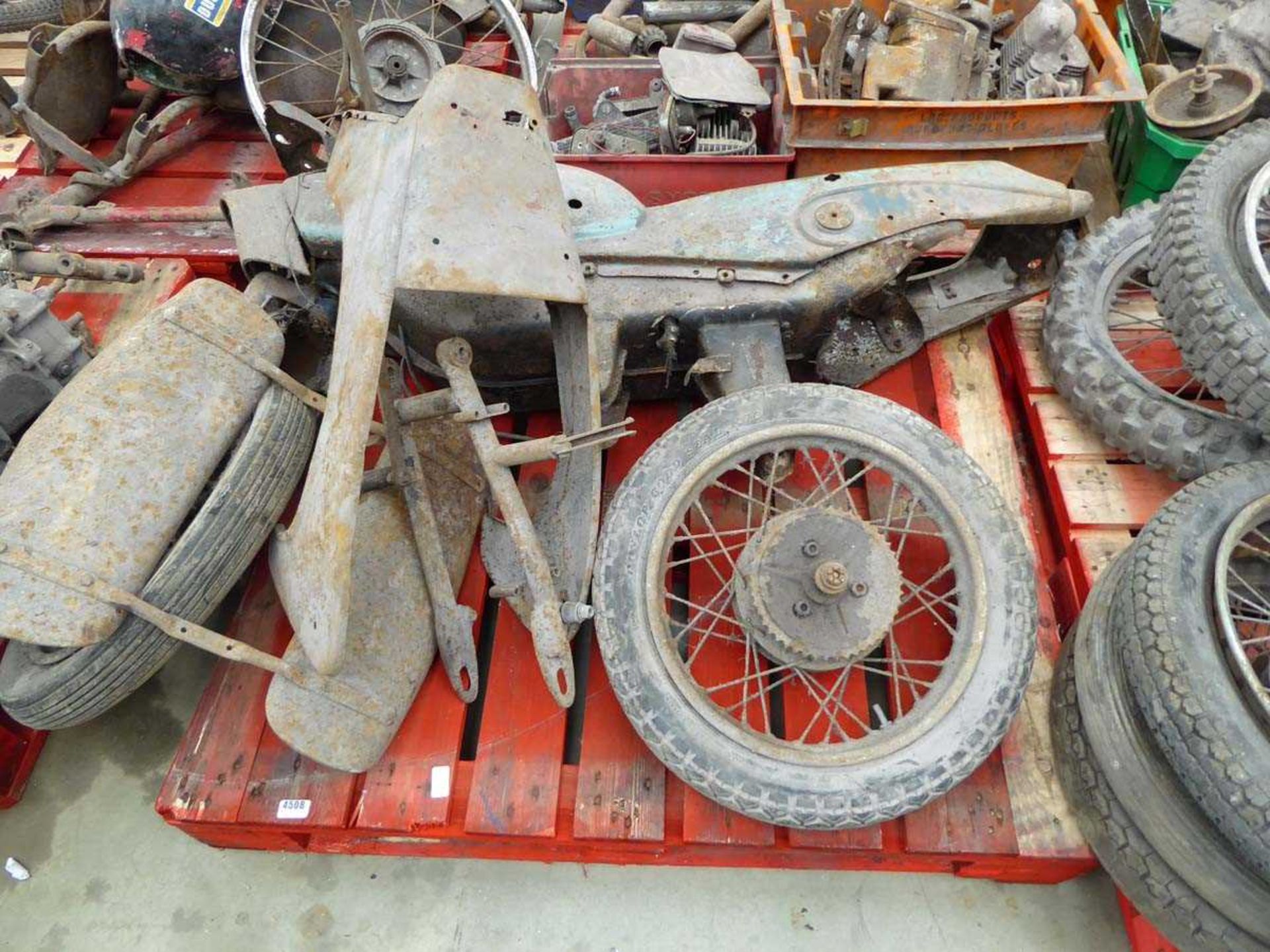 Pallet containing a motorcycle frame with wheels and spare parts