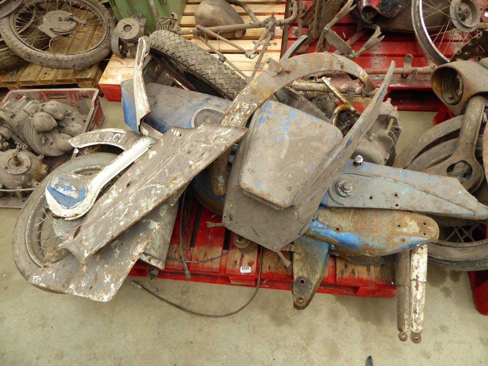 Pallet containing vintage motorcycle frame, spare parts, including wheels and covers