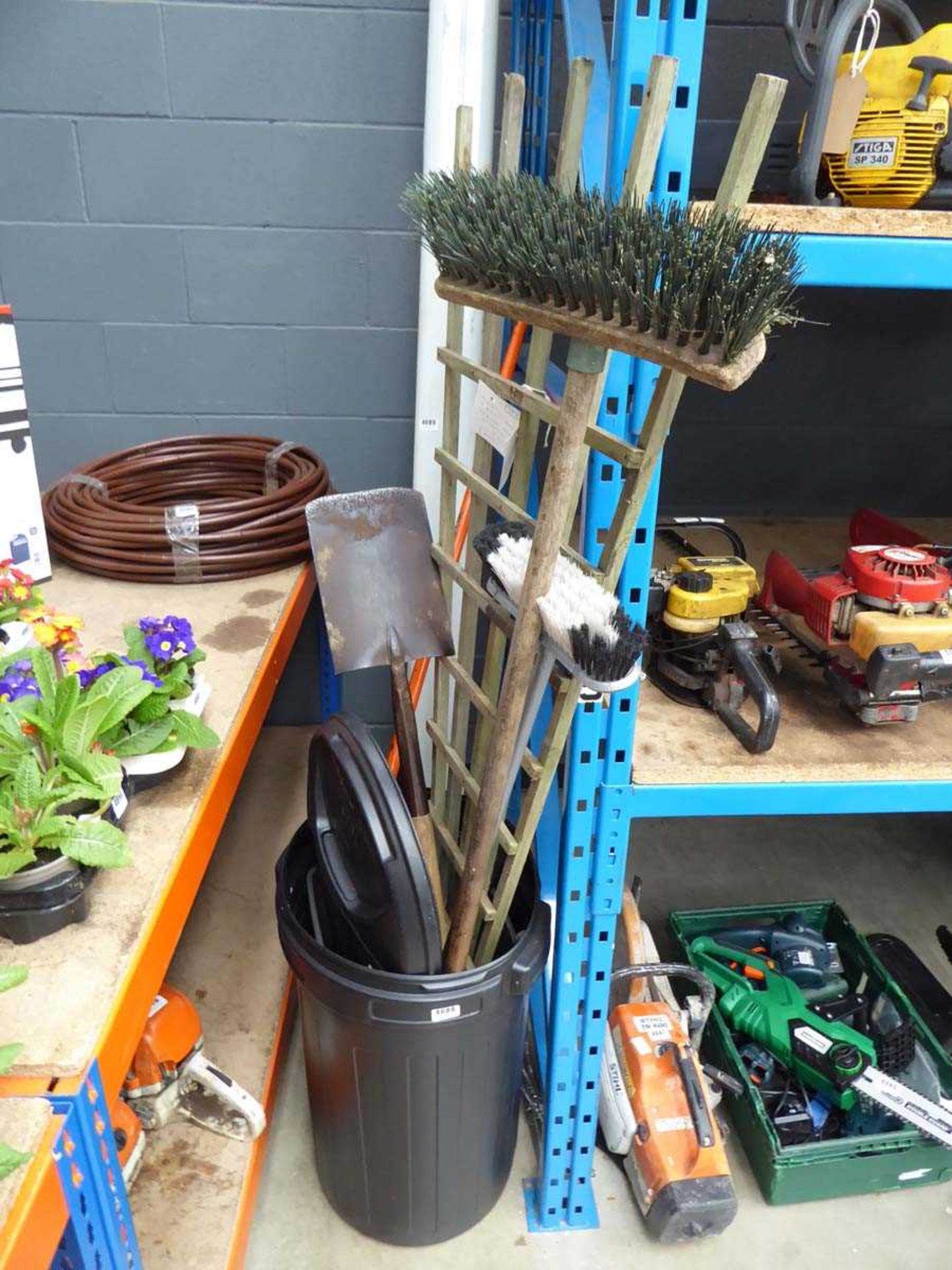 Plastic bin containing garden tools to include brushes, spades, and trellis