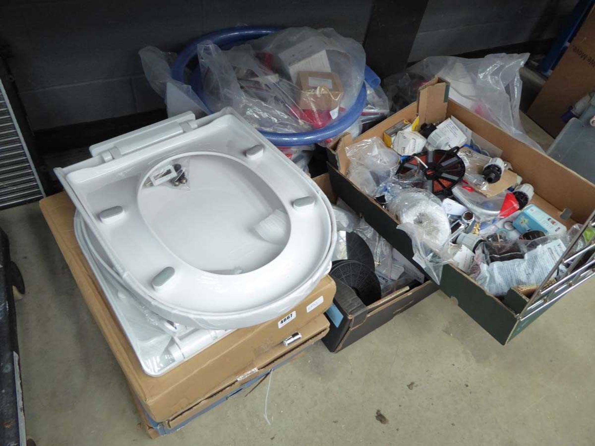 Quarter of an under bay containing toilet seats, filters, plumbing items, pipes, etc