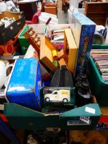 Box containing board games, binoculars, diecast vehicles, and camping stove