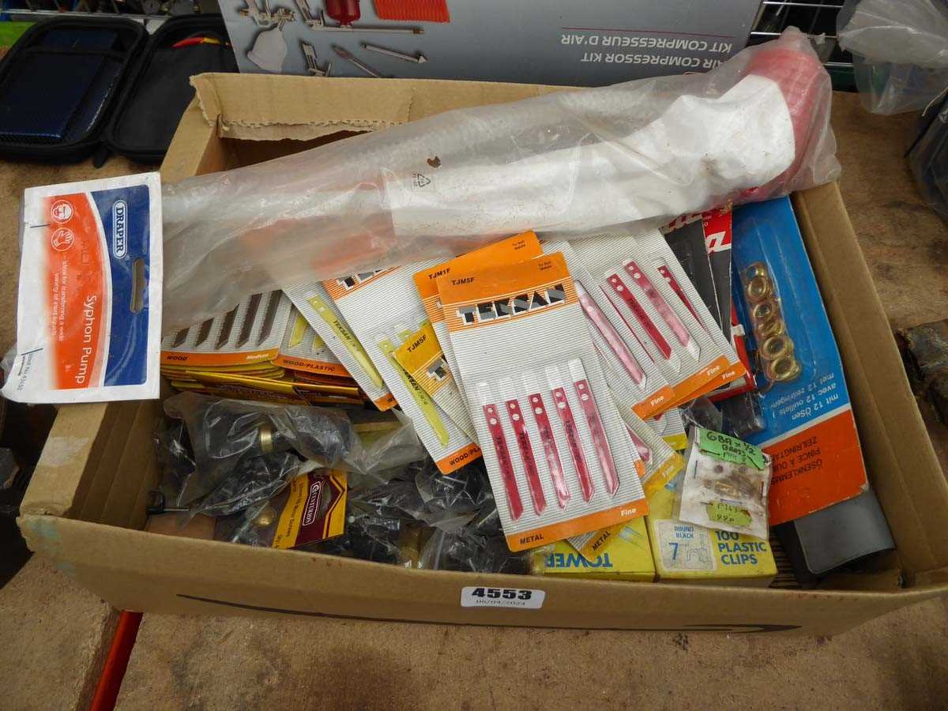 Box containing jigsaw saw blades, plastic clips, screws and other hardware