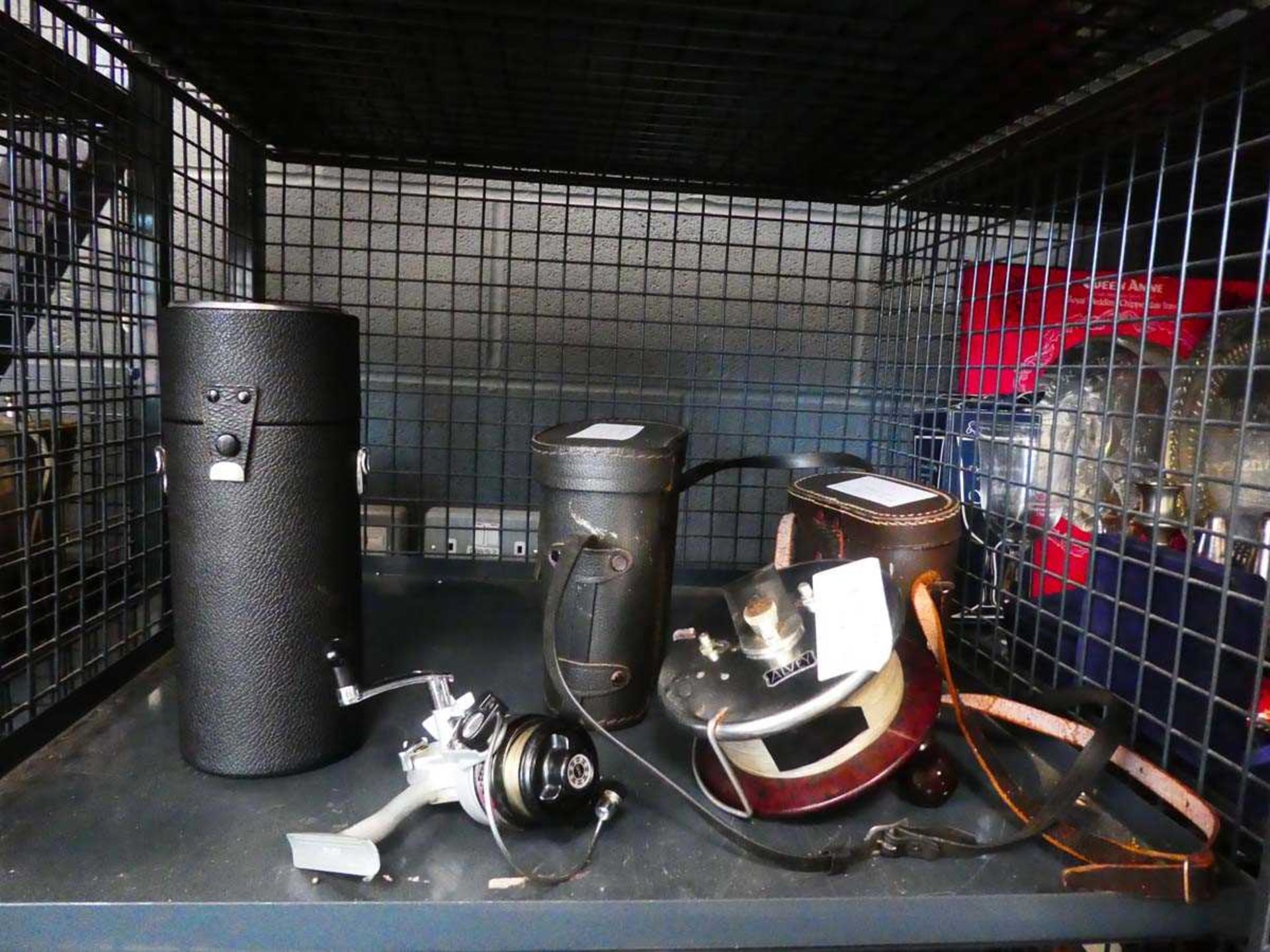 Cage containing binoculars, Livey beach casting reel, spinning reel, plus camera lens