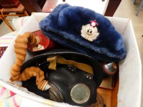 Box containing a Russian military cap, gas masks, and a tin helmet