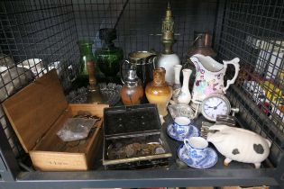 Cage containing coinage, oil lamps plus jugs, quartz clock, piggy bank and cups and saucers