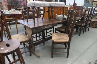 Pair of oak refectory tables with carved acorn emblem plus 10 ladder back and rush seated chairs