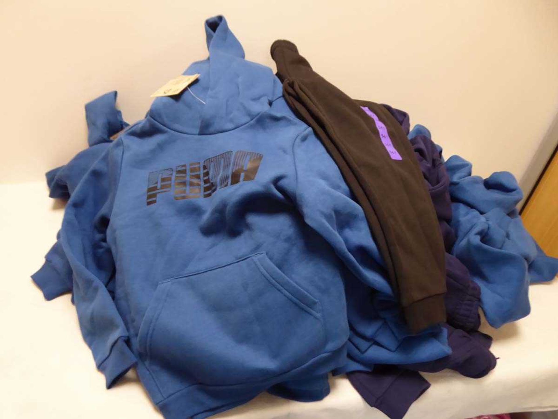 Several kids Puma tracksuit tops and bottoms in various colors and sizes