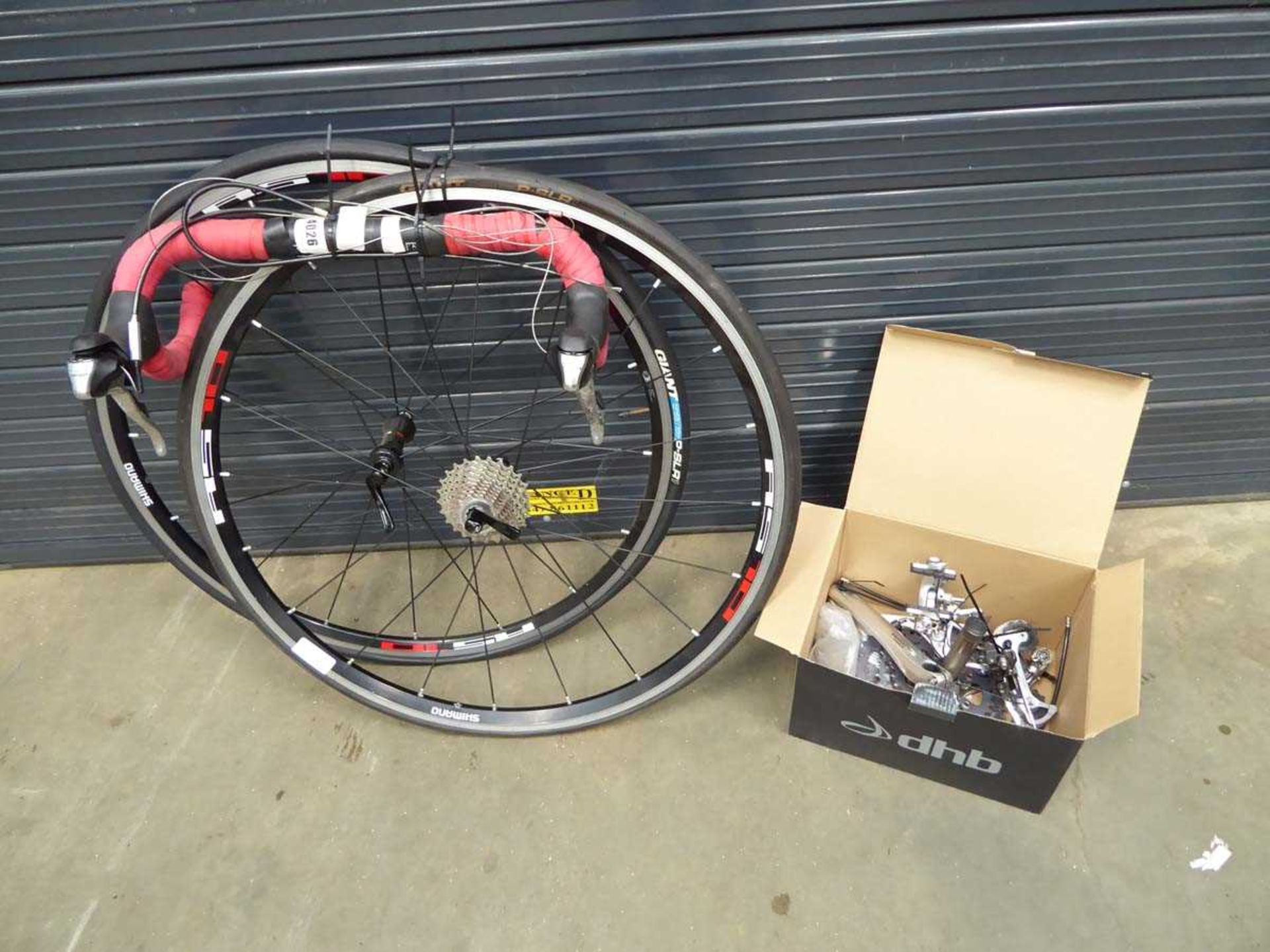 2 racing bike wheels, set of handlebars, and box containing various parts