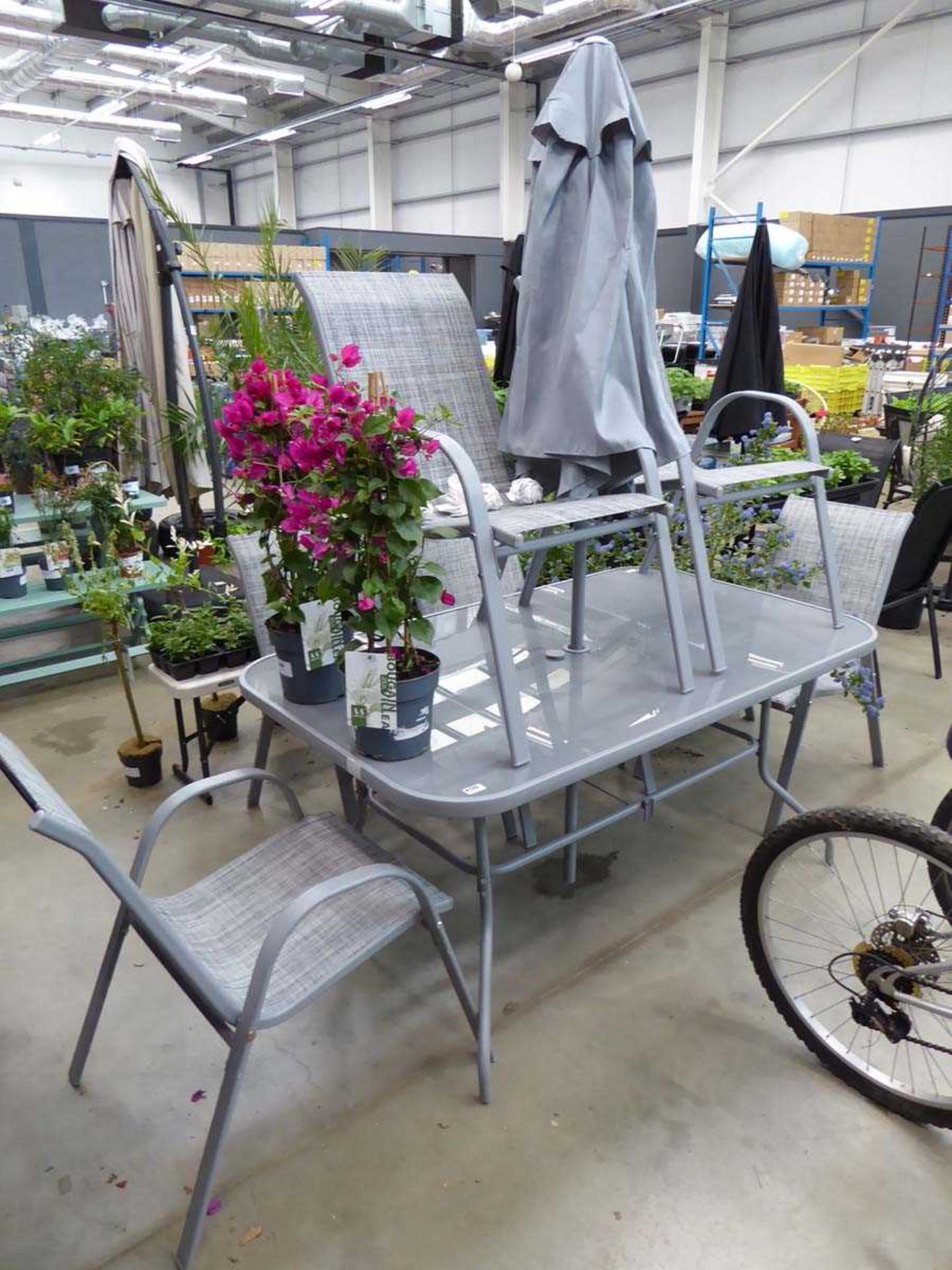 Grey rectangular glass topped metal frame garden table with 6 grey chairs and parasol