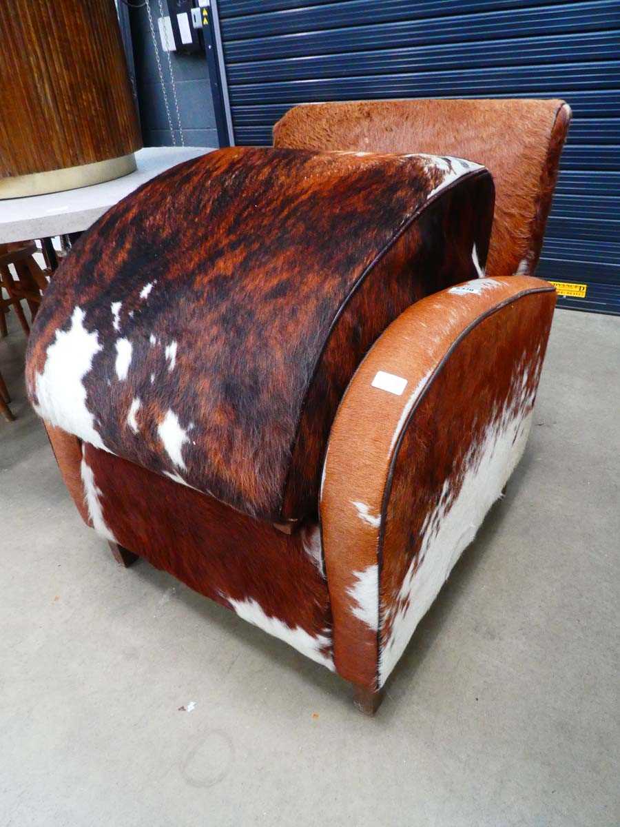 Cowhide upholstered armchair with matching footstool Some scuffing to legs